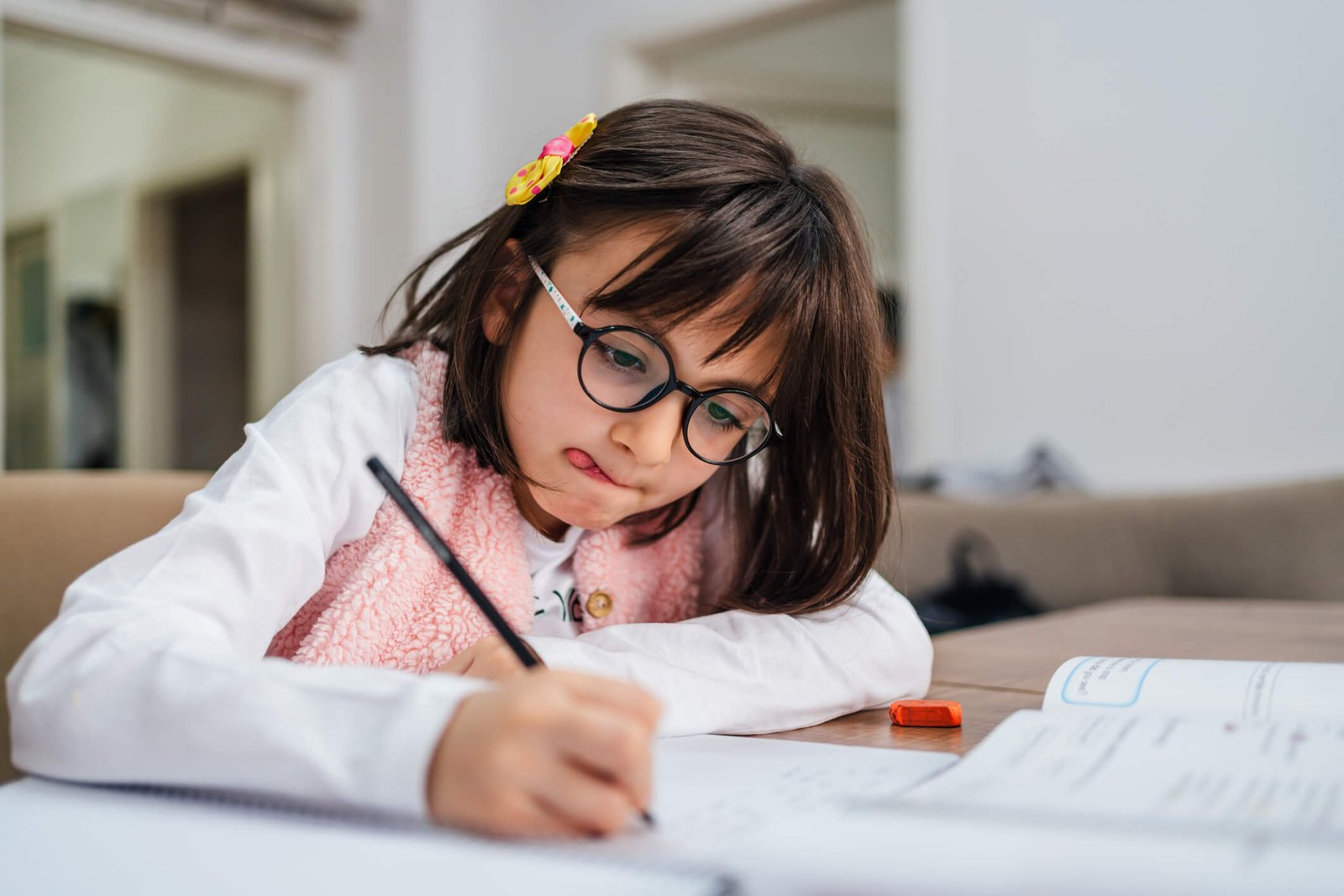 astigmatisme-colombes petite fille portant des lunettes pour une hypermétropie qui fait ses devoirs